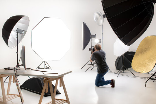 Photographer  Working In Modern Lighting Studio With Many Kinds Of Flash And Accessories. Taking To Empty Area In Look Like Shot To Someone. Idea For Adding People Or Object To Photo