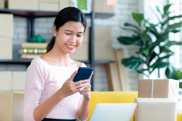 Young Asian beautiful girl is happy smiling to shopping online with smartphones and other order items she buys around her. Concept technology makes us live more comfortable and easy to tread