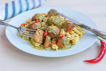 Italian traditional food - fusilli pasta with meatballs and pesto sauce on a white plate