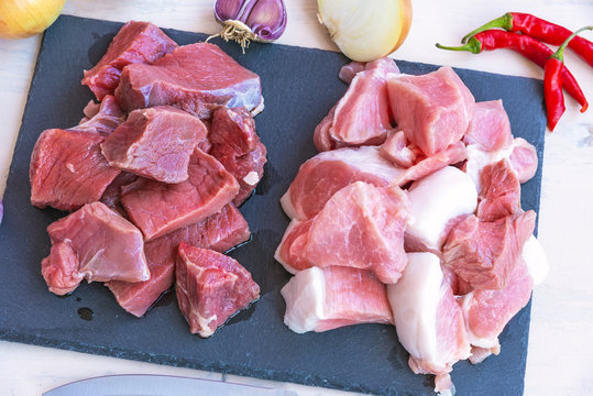 Pieces of raw pork meat and beef and ingredients for minced meat