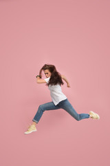 What is there interesting in the distance. seeking pretty happy young woman jumping and grabbing against pink studio background. Runnin girl in motion or movement. Human emotions and facial