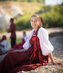 A beautiful girl in Russian national costume pose for the camera on the background of an amazing landscape