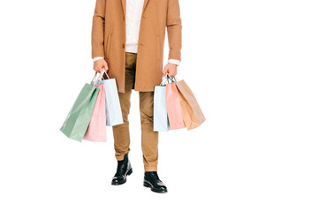 low section of young man holding paper bags isolated on white