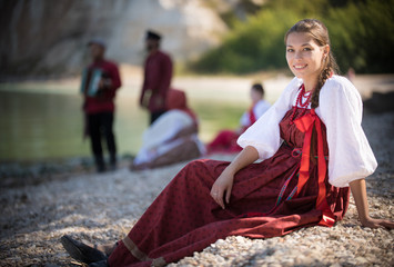 Pretty girl in Russian national costume pose for the camera on the background of an amazing landscape
