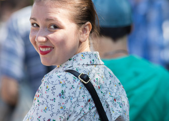 A smiling young woman walks down the road in a crowd