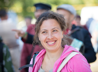 A smiling woman walks down the road in a crowd