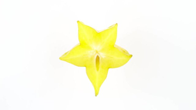Top view from above of one star shaped slice of ripe carambola fruit. Cross section. Slowly rotating on the turntable isolated on the white background. Close-up. Macro.