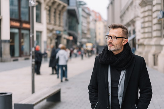 mann mit mantel geht durch die innenstadt