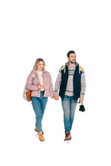 full length view of smiling young couple of tourists with backpacks holding camera and coffee to go isolated on white