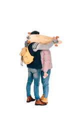 Naklejka premium full length view of young couple hiding faces behind longboard isolated on white