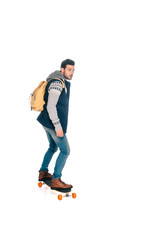 full length view of handsome young man with backpack riding longboard and looking away isolated on white