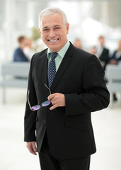 closeup of a serious senior businessman with glasses in hand.