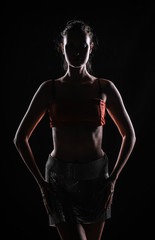 silhouette of a sporty sexy female fitness model on a black studio background