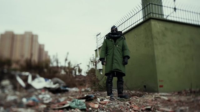 postapocalypse, lonely man walks amid garbage dump and abondoned town