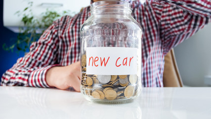 Closeup image of young man with glass jar full of money for buying new car