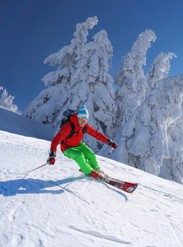 Skier skiing downhill in high mountains against blue sky
