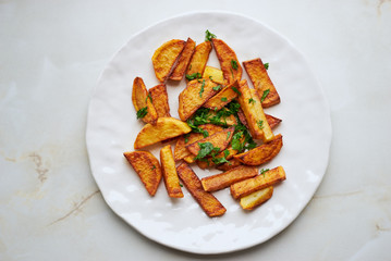 homemade roast potatoes with parsley in a white plate top view