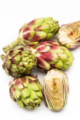 Fototapeta premium Alcachofas enteras y por la mitad sobre fondo blanco aislado. Vista de superior. Copy space