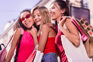 Successful shopping. Positive joyful young women standing together while holding shopping bags