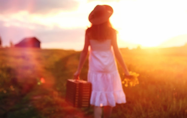 Girl in the spring in the field. A girl with a suitcase walks th