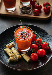 Seasonal tomato soup gazpacho in glasses on dark wooden table background. Vertical. Food and drink, still life, diet and nutrition concept. Meditteranean food.