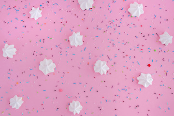 White meringues and colorful confetti on pink background.