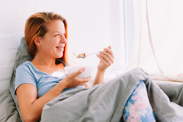 Young woman eating breakfast in bed
