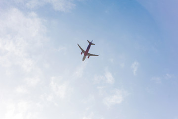 Fototapeta na wymiar low angle view of plane flying in blue cloudy sky