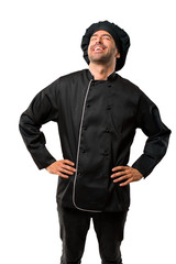 Chef man In black uniform posing with arms at hip and laughing on isolated white background