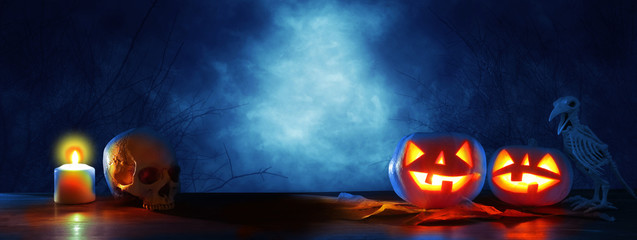 Halloween holiday concept banner. Pumpkins over wooden table at night scary, haunted and misty...