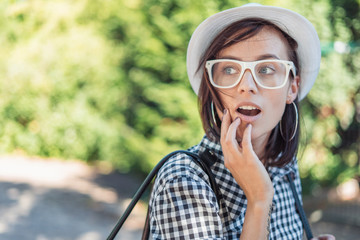 Astonished young woman looking to something. Trendy girl in the park