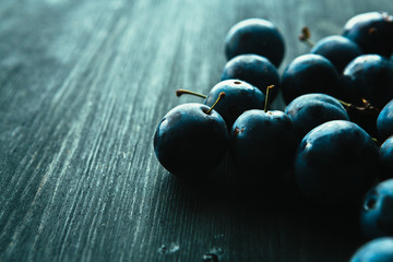 many fresh plums on black background close up