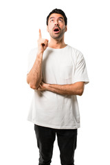 Young man with white shirt standing and thinking an idea pointing the finger up on isolated white background