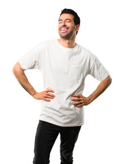 Young man with white shirt posing with arms at hip and laughing on isolated white background