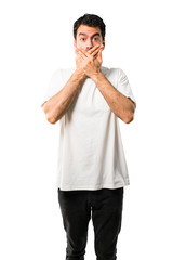 Young man with white shirt covering mouth with both hands for saying something inappropriate. Can not speak on isolated white background