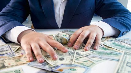 Conceptual photo of greed and avarice. Businessman grabbing money lying on office desk