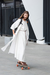 Smiling Jesus in robe and crown of thorns skating on longboard on street