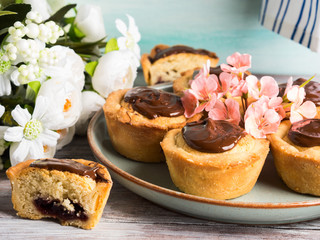 Cakes with frangipane, cherry jam and chocolate frosting. Romantic table setting with flowers. Mother's day card