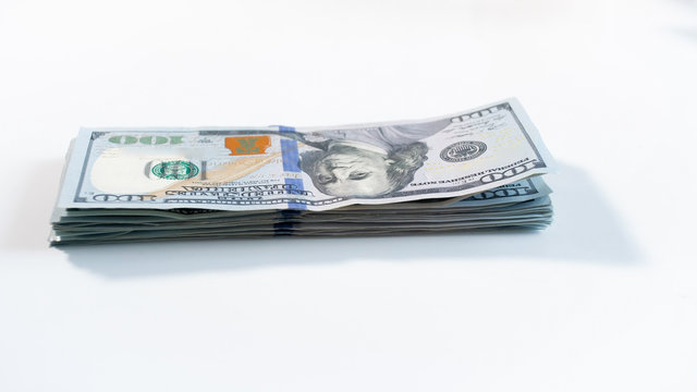 Closeup image of big stack of 100 US dollars lying on white wooden desk