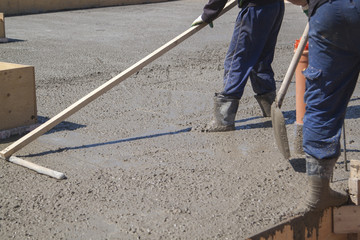 worker leveling fresh concrete slab with a special working tool