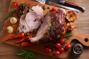 Baked ham with vegetables: carrots, onions, tomatoes, garlic and herbs on chopping board. View from above, top studio shot © freeskyline