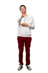 A full-length shot of a Man with glasses and listening music pointing with finger at someone and laughing a lot on white background