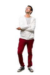 Naklejka premium A full-length shot of a Man with glasses and listening music stand and looking up while smiling on white background