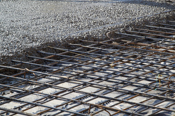 pouring concrete into prepared place with reinforced metal frame