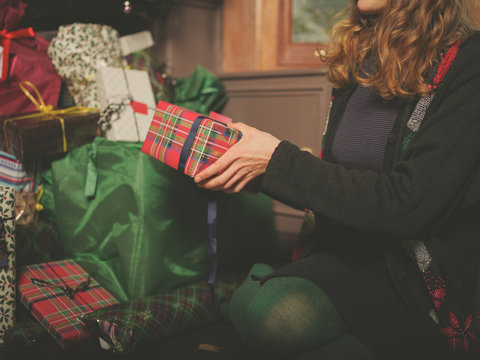 Young woman placing christmas present under tree