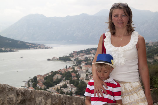 concept of family adventure. Mother traveling with children is depicted on the observation deck on the mountain overlooking the famous spectacular view of the Bay of Kotor, Montenegro