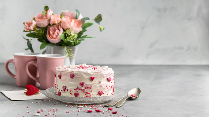 Cake with small hearts and colorful sprinkles on a plate with  two cups of coffee. Grey stone background. Romantic love background. Valentine's day, Mother's Day, Birthday Cake card.