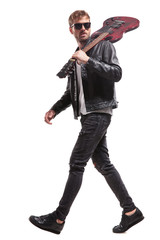 side view of handsome rocker walking with guitar on shoulder