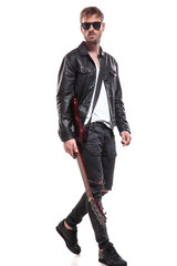handsome fashion man stepping to side while holding guitar