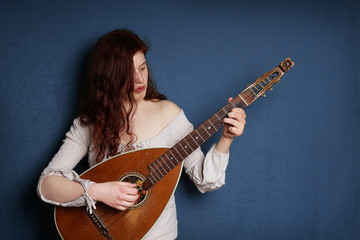 young woman playing old vintage lute string instrument